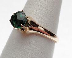 This is a 1940s-1950s classic! This is a six prong solitaire ring that has a 5.50 mm round synthetic (man made) green stone for the birth month of May. The stone has a fancy faceted top, similar to a rose cut on the top but with a pavilion like a modern cut round stone. There are some abrasions around the girdle, but the ring looks brand new other than that! The ring is stamped 10 kt and weighs 2.9 grams. Ring is sie 6.z Formal Emerald Ring With Tension Setting, Classic Emerald Ring With Round Band For May Birthstone, Classic Round Emerald Ring With Tension Setting, Classic Oval Emerald Ring With Tension Setting, Classic May Birthstone Ring With Center Stone, Classic Emerald Jewelry With Round Band, Classic Green Bezel Set Birthstone Ring, Classic Emerald Round Band Jewelry, Antique Green Emerald Ring With Prong Setting