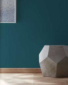 a vase sitting on top of a hard wood floor next to a blue painted wall