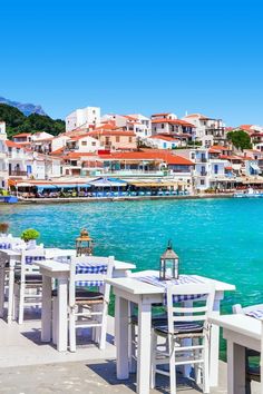 an outdoor dining area overlooking the water with tables and chairs set up on it's side