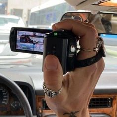 a man holding up his cell phone to take a photo in the car with other cars behind him