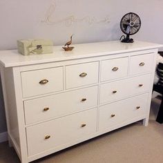 a white dresser sitting in a bedroom next to a wall