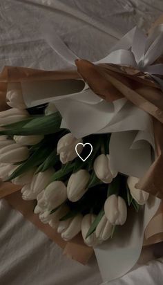 a bouquet of white tulips wrapped in brown paper with a heart on it