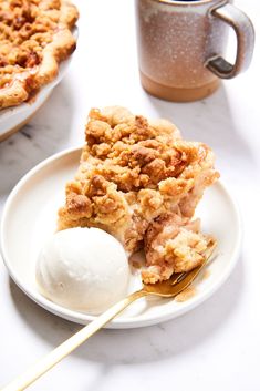 a piece of pie on a plate with ice cream and a fork next to it