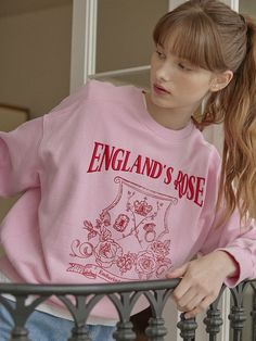 a young woman wearing a pink sweater with england's rose printed on the front