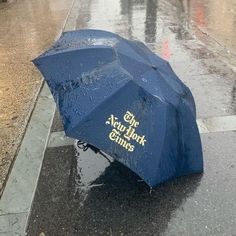 a blue umbrella that reads the new york times on it's side in the rain