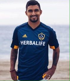 a man standing in front of the ocean wearing a soccer uniform