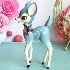 a blue and white deer figurine next to pink flowers