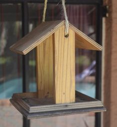 a wooden birdhouse hanging from a rope