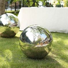 two shiny balls sitting in the grass near a table