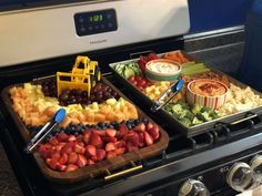 two trays filled with different types of food on top of an oven door sill