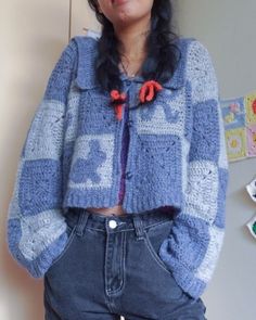 a woman standing in front of a wall wearing a blue and white jacket with red buttons