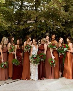 a group of women standing next to each other wearing dresses and holding bouquets in their hands