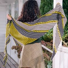 a woman is standing on the porch with her arms wrapped in a shawl,