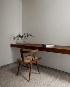 a wooden chair sitting in front of a desk with a plant on top of it