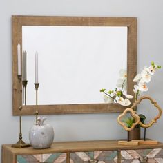 a mirror sitting on top of a dresser next to a vase with flowers