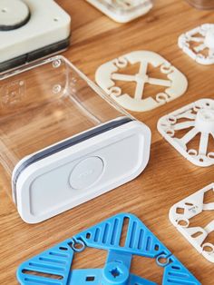 several plastic objects sitting on top of a wooden table next to scissors and cutters