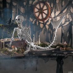 a skeleton sitting on top of a table with candles