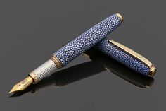 a fountain pen sitting on top of a black table next to another pen with gold trimming