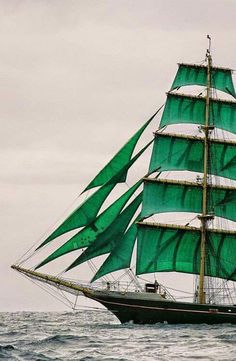 a large green sail boat in the ocean