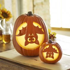 two carved pumpkins sitting on top of a wooden table