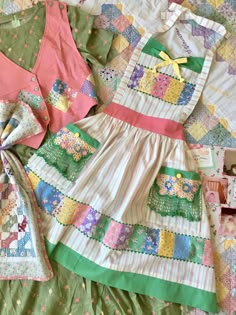 an assortment of children's clothing laid out on a quilted bed coverlet