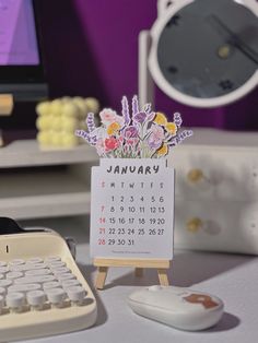 a calendar sitting on top of a wooden stand next to a keyboard and computer monitor