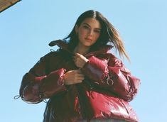 a woman in a red jacket is posing for the camera with her hand on her hip