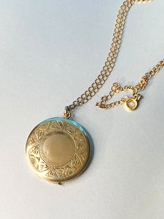 "Up for sale is vintage locket from the approximate 30-40's era with a beautiful engraved floral design on front. MARKINGS: The inside is marked 1 20 12kt GF and the initials MB in a cartouche.  The chain is marked  1/20 12 kt gf and a makers mark I cannot discern. I tried to find out who the maker was but had no luck. If one of you out there knows this maker, please contact  me so that I can make notes for my future listings and update this one. DESCRIPTION: This beautiful locket is 1\" in diameter. There is an engraved floral pattern that goes all the way around the front. There is a blank center where you could put your own initials or a special date. It locks on the top of the locked and a fingernail will open it. It has both the chucks on the inside and one side has the protective pho Antique Medallion Locket Necklace Stamped 14k, Victorian Round Locket Necklace Stamped 14k, Vintage 14k Gold Locket Necklace, Antique Gold Locket Necklace Stamped 14k, Vintage 14k Gold Locket Necklace Stamped 14k, Vintage Gold Locket Necklace Stamped 14k, Vintage 14k Gold Locket Necklace With Vintage Charm, Victorian 14k Stamped Round Locket Necklace, 14k Gold Locket Necklace With Vintage Charm