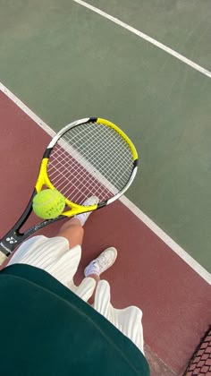 a person holding a tennis racquet on top of a tennis court with a ball in the air