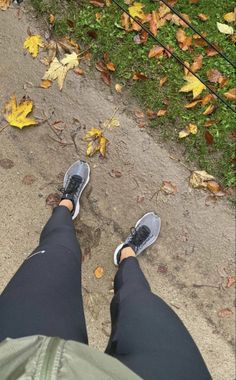 the legs and feet of a person standing in front of some leaves on the ground