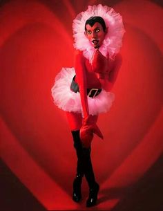 a woman in a red dress and black boots posing for a photo with a heart shaped background