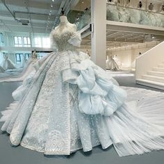 a dress is displayed on display in a large room with white walls and floor to ceiling windows