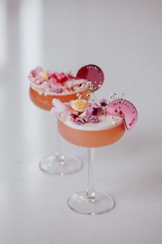 two glasses filled with drinks sitting on top of a white table next to each other