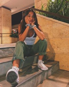 a woman sitting on some stairs with her hands under her chin and looking at the camera