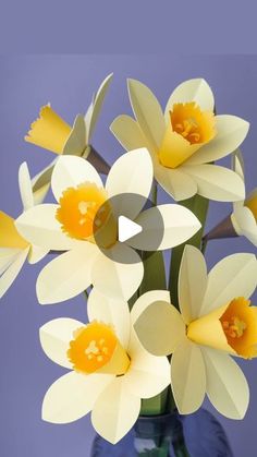 a vase filled with yellow and white flowers on top of a blue table next to a purple wall