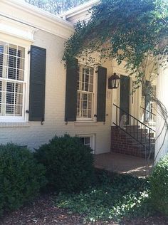 a white house with black shutters and trees