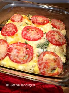 a casserole with tomatoes and cheese in a glass dish on a red cloth