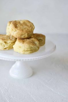 three biscuits sitting on top of a white cake plate