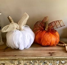 two decorative pumpkins sitting on top of a wooden shelf next to a candle holder