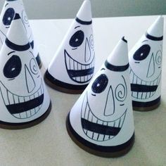 four white and black ceramic faces on small cones