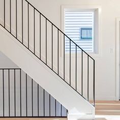 an empty room with white walls and black railings on the bottom floor, next to a set of stairs