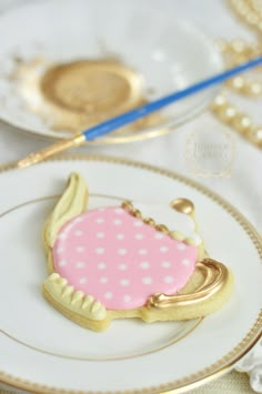 a decorated cookie sitting on top of a white plate next to a blue and gold fork