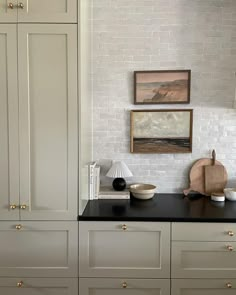 a kitchen with white cabinets and black counter tops in front of a painting on the wall