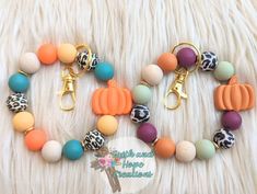 an assortment of colorful beads and charms on a white furnishing background with the words hello autumn written in gold