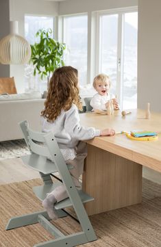 two children sitting at a table with chairs