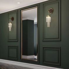 an empty room with green walls and gold framed mirrors