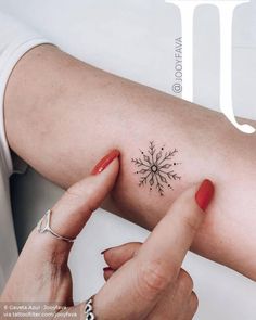 a woman's arm with a small snowflake tattoo on her left shoulder