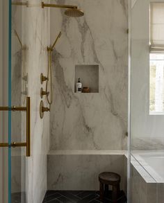 a bathroom with marble walls and flooring next to a bathtub in the corner