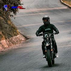 a man riding a motorcycle down a curvy road with trees in the background