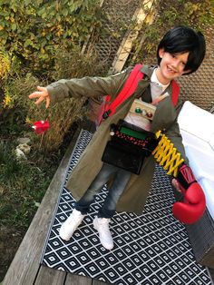 a young boy dressed in costume standing on a deck with his hands out to the side